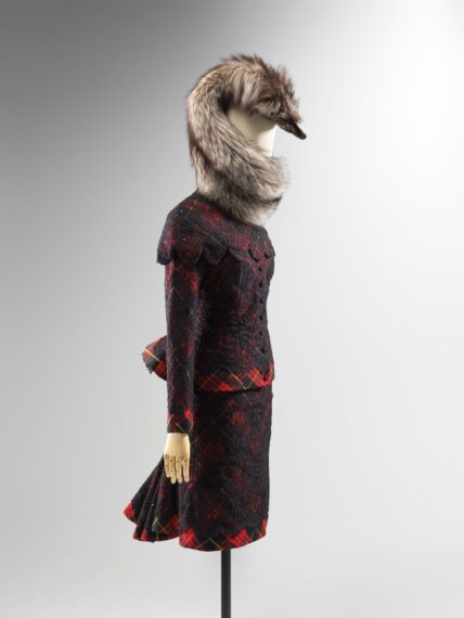 Mannequin wearing a fur stole and vintage-style plaid suite.