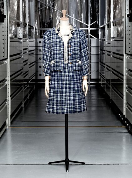 The image shows a mannequin dressed in a matching blue-and-white plaid jacket and skirt.