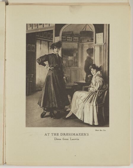 Black-and-white photo of two women in early 20th-century fashion in a dressmaker's shop.