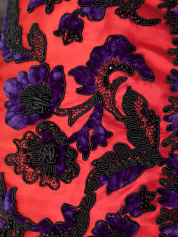 Close-up view of a red dress with black and purple floral patterns.