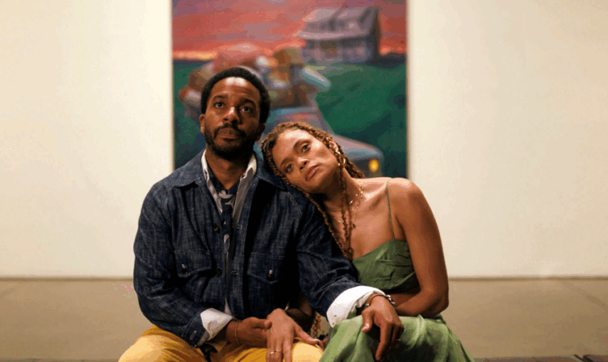 Man and woman sitting closely together in front of a painting.