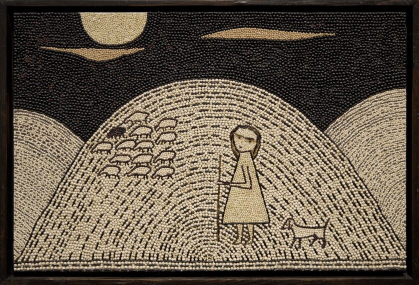 Beaded artwork of a person with a dog on a hill under a moon.