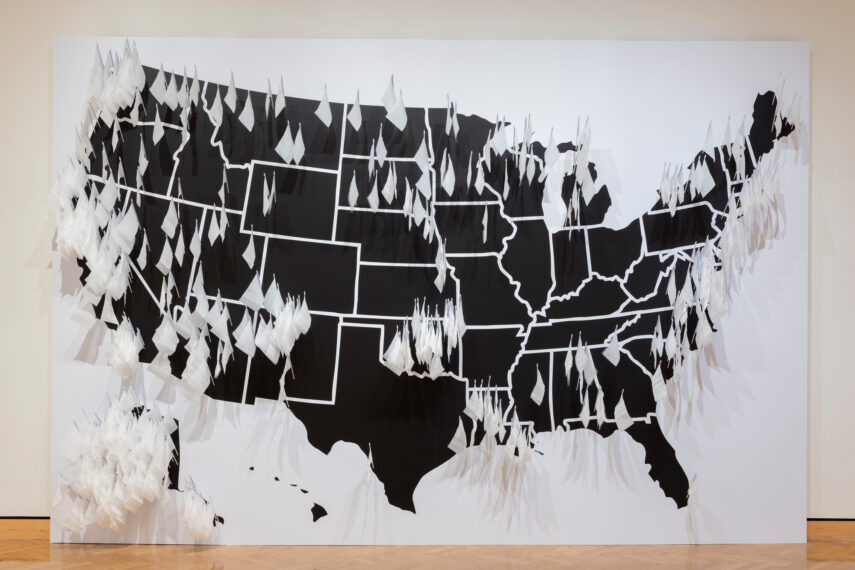 Photo of a black-and-white map of the United States with fabric protrusions, leaning against a wall.