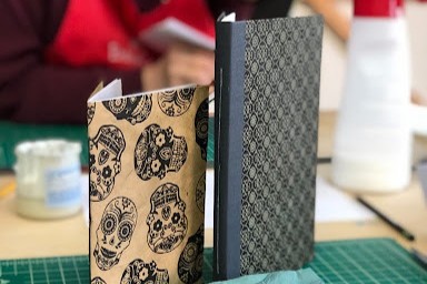 Two patterned notebooks standing upright on a green cutting mat.